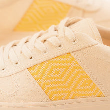 Charger l&#39;image dans la galerie, Zoom sur le côté de la basket, montrant de près le motif ethnique jaune brodé sur la toile beige.
Les lacets en coton beige et la texture du tissu naturel sont clairement visibles.