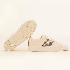 Beige Sneaker auf hellem Hintergrund – eine Schuhsohle sichtbar, die andere zeigt das detailreiche Ethno-Muster.
Vegane Lifestyle-Sneaker mit nachhaltiger Sohle und traditioneller Webkunst.