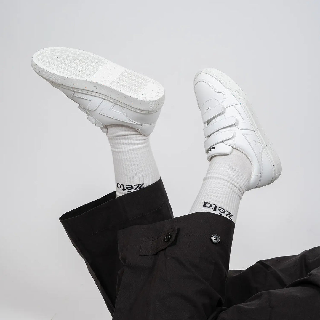 Look casual avec les baskets blanches à scratch Alpha portées, jambes croisées en l’air