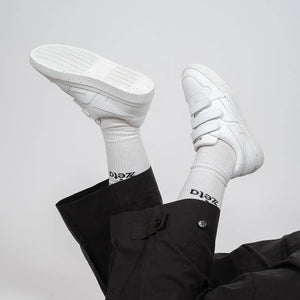 Look casual avec les baskets blanches à scratch Alpha portées, jambes croisées en l’air