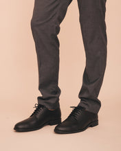 Charger l'image dans la galerie, Black dress shoes worn with gray pants on a beige background