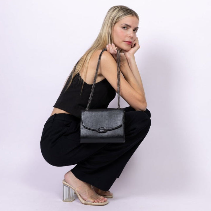 Sac à main vegan noir effet lézard porté par une femme assise, sac bandoulière Mini Paname Ashoka Paris
